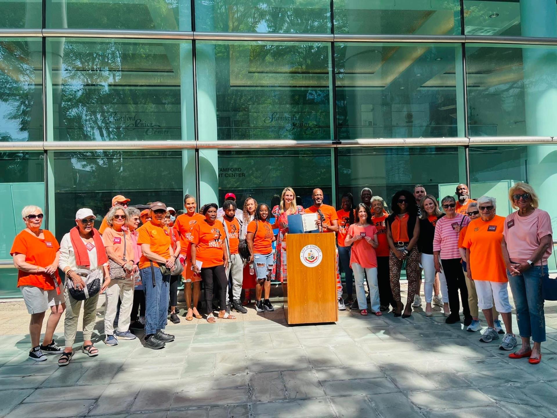 Mayor Simmons presents a proclamation on Gun violence awareness day. She is surrounded by activists in orange